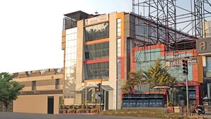 A modern hotel with a glass facade, a sign for 'Astor Hotel', and a construction site nearby. - Treebo Astor HSR Layout (Bengaluru)