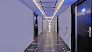 A modern hotel hallway with a long corridor, doors on both sides, and a ceiling with recessed lighting. - Treebo Astor HSR Layout (Bengaluru)