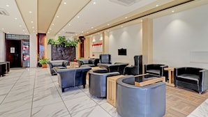 A modern reception area with leather sofas, a wooden coffee table, and a Buddha statue. - Treebo Astor HSR Layout (Bengaluru)