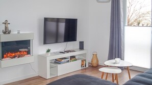 Ein modernes Wohnzimmer mit Kamin, Flachbildfernseher, weißem Unterhaltungsschrank, einem kleinen Tisch und einer Couch.