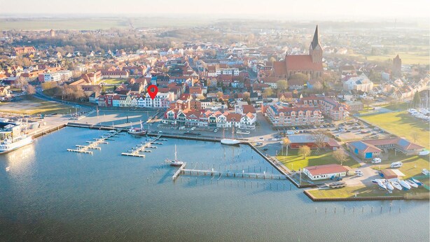 Eine Vogelperspektive einer Stadt mit einem Yachthafen, Gebäuden und einer Kirche.