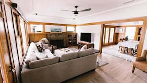 A living room with a sofa, a fireplace, a television, and a dining area with a table and chairs. - Close to the beach, train and all the downtown fun! (Oceanside)