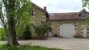 A two-story house with a tiled roof, a gravel driveway, and a large garage door.