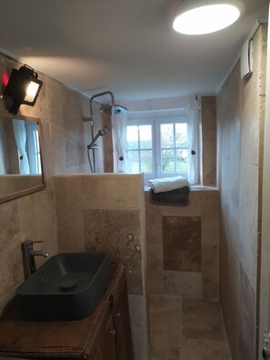 Bathroom features a standalone sink, mirror, and shower area with handheld showerhead.