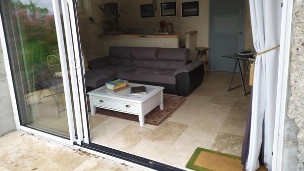 A living room with a grey sofa, a white coffee table, and a sliding glass door leading to an outdoor area.
