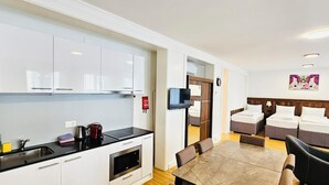 Una habitación de hotel moderna con kitchenette, comedor y dormitorio con dos camas.