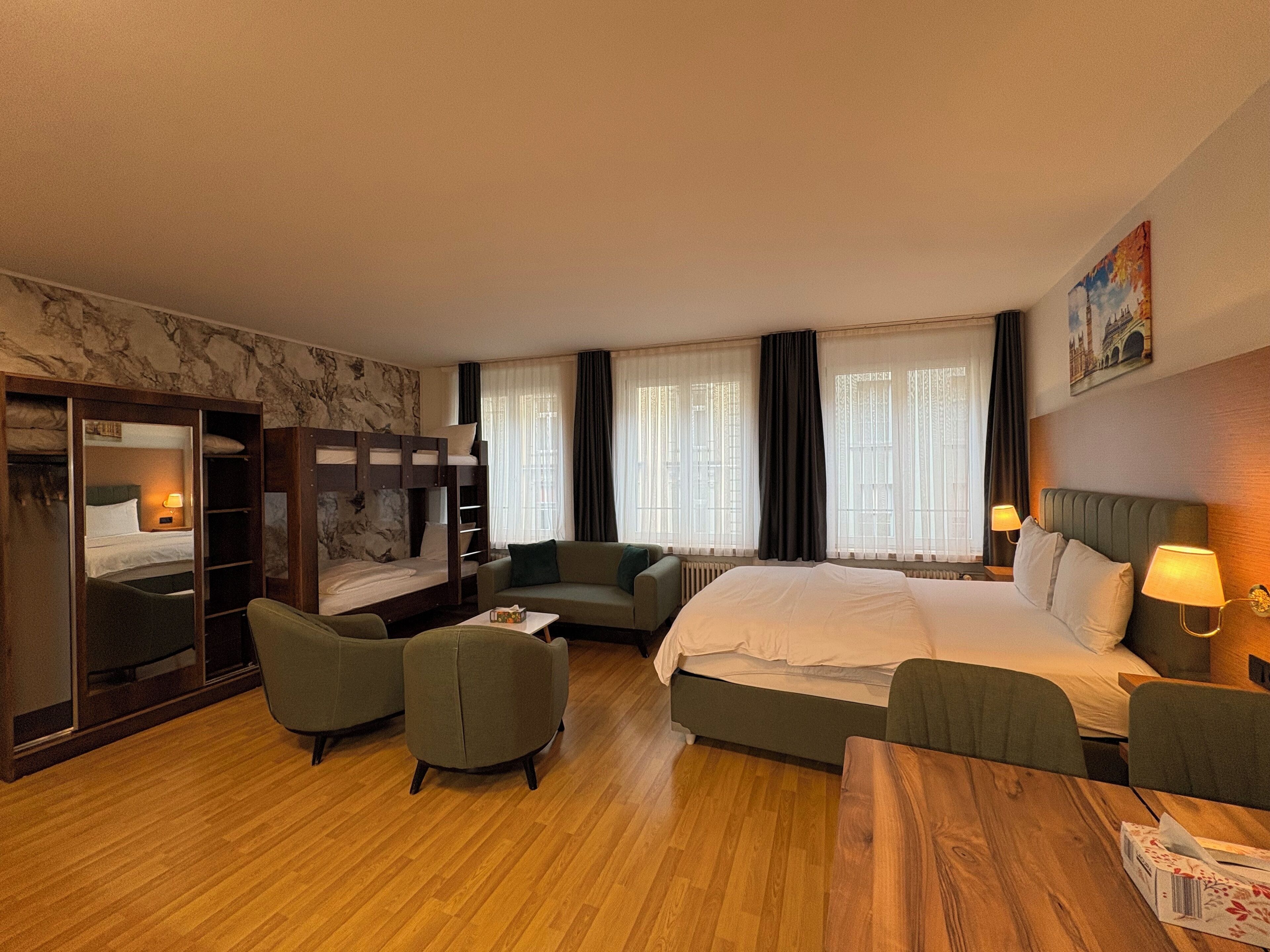 Une chambre d’hôtel avec un lit superposé, un canapé, une table et un bureau.