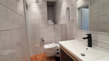 Une salle de bain moderne avec un lavabo blanc, un robinet noir et un grand miroir.