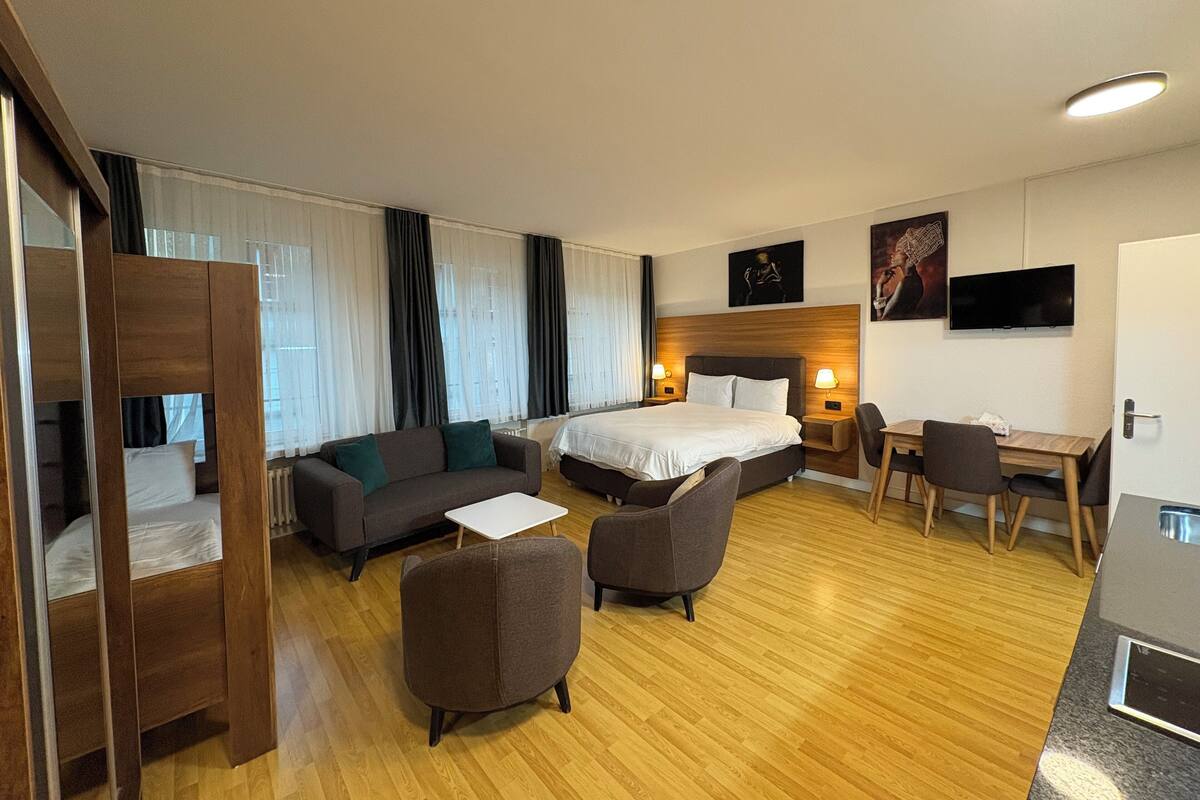 Ein Hotelzimmer mit Bett, Sofa, Schreibtisch und Fernseher.