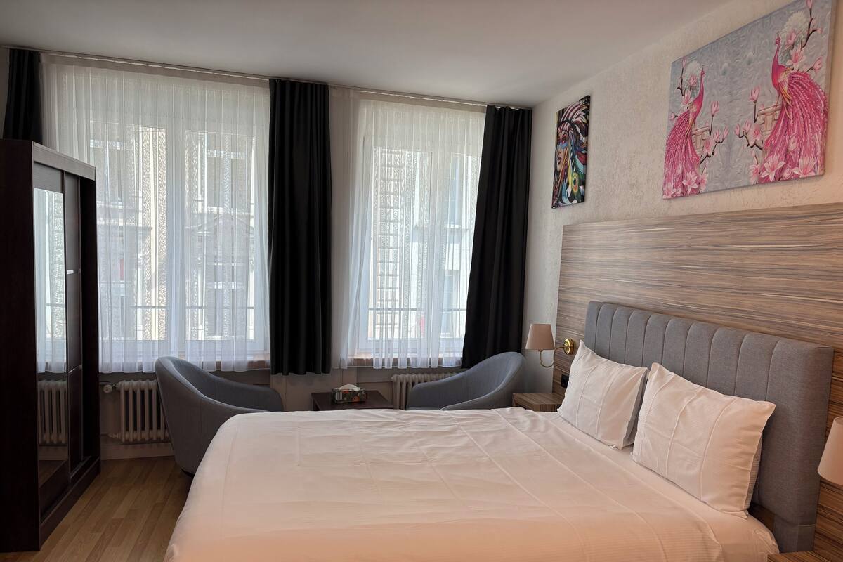 Ein modernes Hotelzimmer mit einem großen Bett, zwei Sesseln, einer Heizung und einem Bild an der Wand.