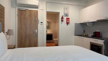 Une chambre d’hôtel comprenant un lit, une salle de bain, un coin cuisine et une horloge fixée au mur.