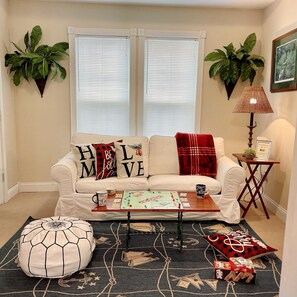 Una sala de estar acogedora con sofá, mesa de centro, juego de mesa y cojines decorativos.