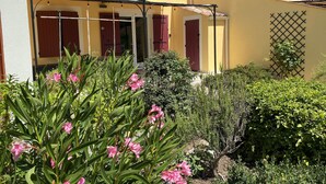 Un edificio amarillo con un patio techado, contraventanas rojas y un ventanal con celosías.