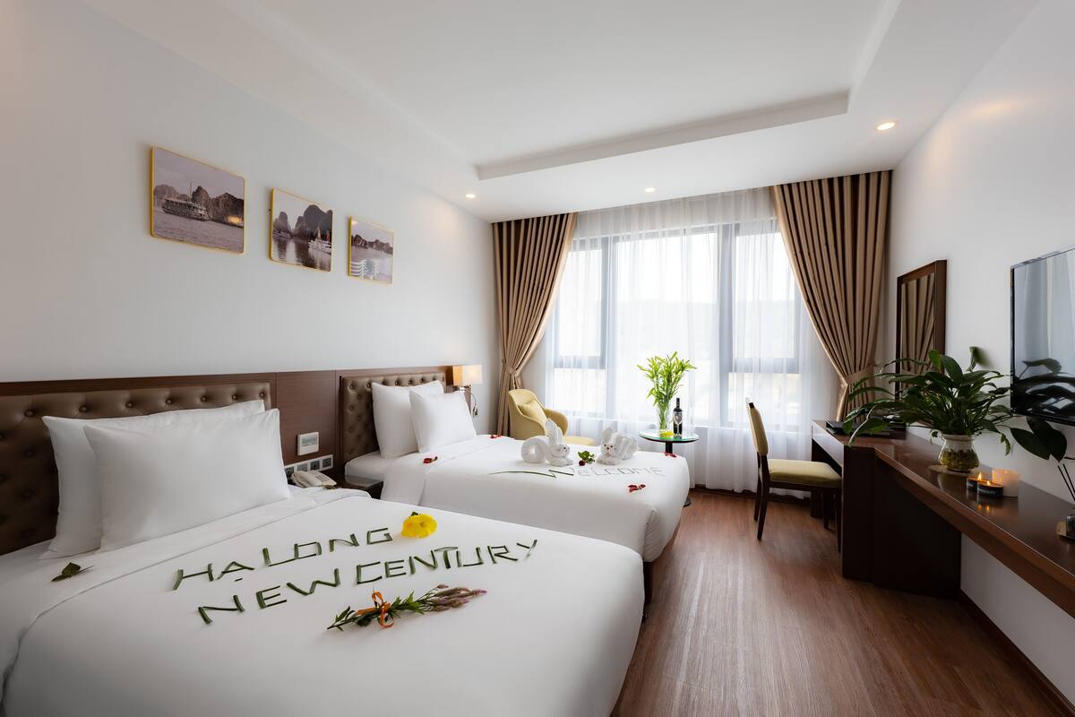 Een hotelkamer met twee bedden, een bureau, een stoel, een televisie en een raam met gordijnen.