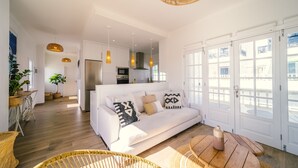 Ein modernes Wohnzimmer mit einem weißen Sofa, Korbstühlen und einem Holztisch.