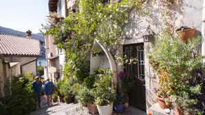 Un estrecho callejón con escalones que conducen a la entrada de un edificio, rodeado de macetas con plantas y flores.