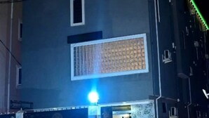 Ein mehrgeschossiges Gebäude mit einem markanten Eingang, der eine Marmorfassade und ein Metallgitter aufweist.