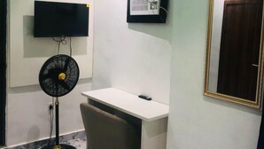 Ein kleiner, moderner Raum mit Schreibtisch, Stuhl und einem an der Wand befestigten Fernseher.