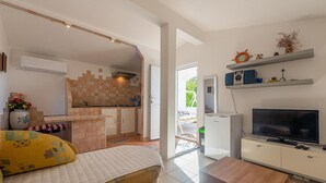 Ein kompakter Wohnbereich mit Küchenzeile, Fernseher und Bett.
