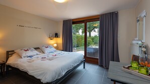 Ein Schlafzimmer mit einem Bett, einem Tisch mit grünem Glas, Blick auf Grünfläche draußen und einer Wand mit einem motivierenden Zitat.