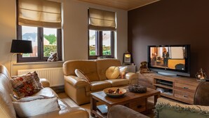 Ein Wohnzimmer mit einem beigefarbenen Sofa, einem Couchtisch und einem Fernseher.