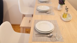 Ein Esszimmer mit Geschirr, Besteck und einem Glas.