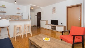 Ein modernes Wohnzimmer mit Couchtisch aus Holz, einem roten Sessel und einem Fernsehschrank.