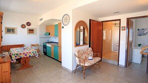 A cozy kitchen with a dining area, a wooden table with a colorful tablecloth, and a wicker chair. - app.to Scirocco (Ragusa)