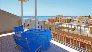 A balcony with a table set for two, overlooking a coastal cityscape. - app.to Scirocco (Ragusa)