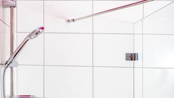 A modern shower with a chrome fixture, a white tiled wall, and a bright pink ceiling.