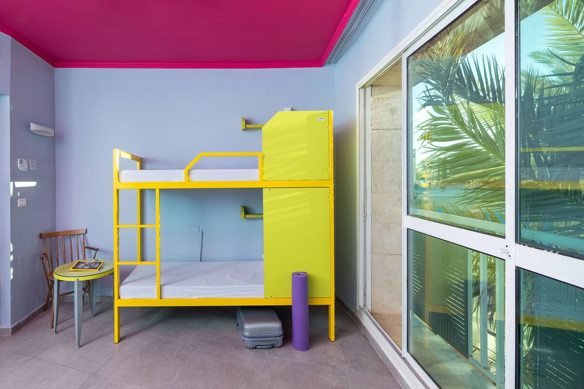 A bunk bed room with a window, a chair, and a suitcase.