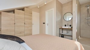 Quarto com cama, guarda-roupa, banheiro com chuveiro e espelho.