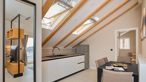 Cozinha moderna com claraboias, área de jantar com mesa e cadeiras, e vista para a cidade.