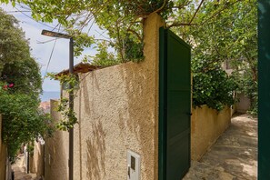 A narrow alleyway with textured walls, a green door, and a street lamp. - Hedera Estate, Hedera A32 (Dubrovnik)