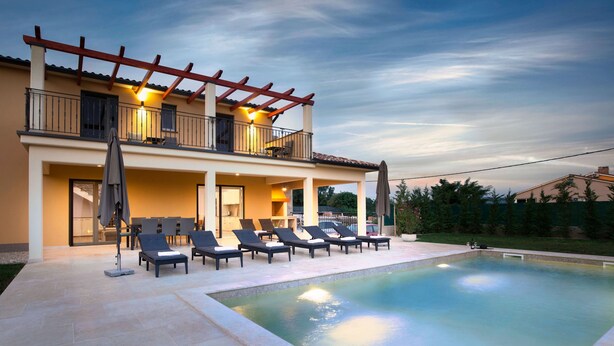 A two-story house with a swimming pool, outdoor seating, and a covered patio area.