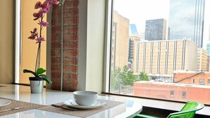 A modern room with a round white table, a green chair, a small potted orchid, and a bowl on the table.