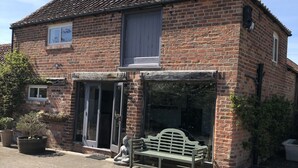 A brick building with a tiled roof, a bench outside, and a statue of a figure. - Impeccable Cottage Suitable for 2 Adults & 1 Child (York)