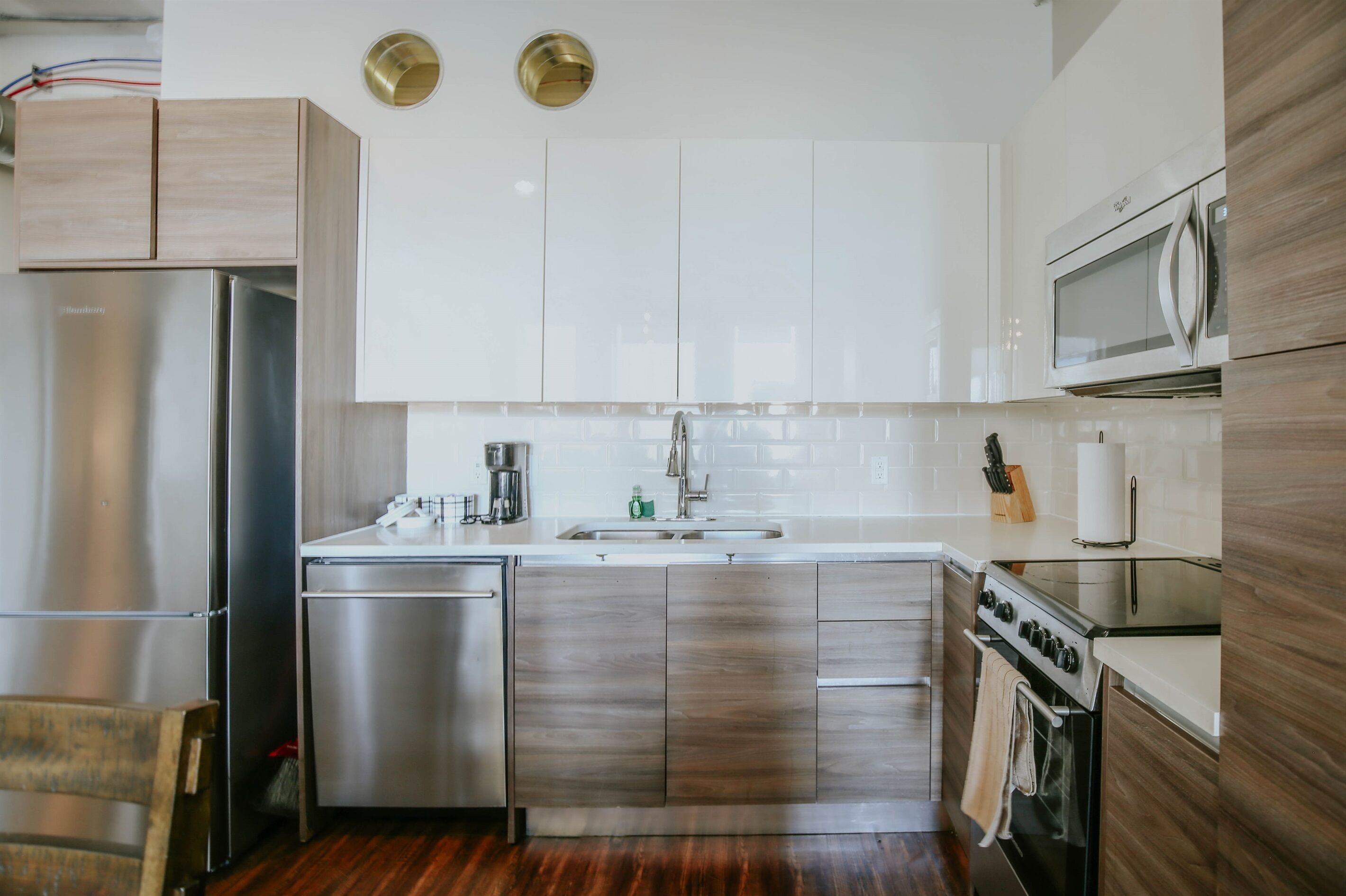 Une cuisine moderne dotée d’appareils électroménagers en acier inoxydable, de meubles blancs et d’un plancher en bois.
