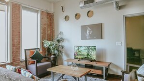 Una sala de estar moderna con un sofá, una mesa de centro, un televisor y una planta.