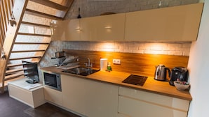 Een moderne keuken met een houten aanrecht, roestvrijstalen apparatuur en een bakstenen muur.