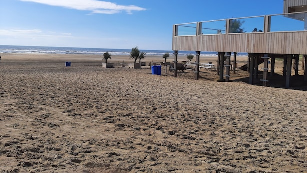 Una playa con una estructura de madera, posiblemente una torre de salvavidas, y un cielo despejado.