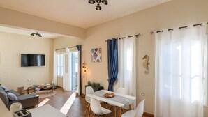 Una sala de estar moderna con comedor, televisor de pantalla plana y área de cocina con cafetera.