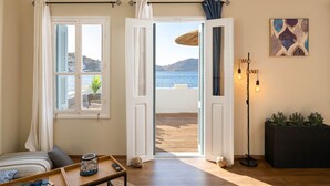 Una habitación con vista al mar, una cama, una mesa con bandeja y una lámpara de pie.