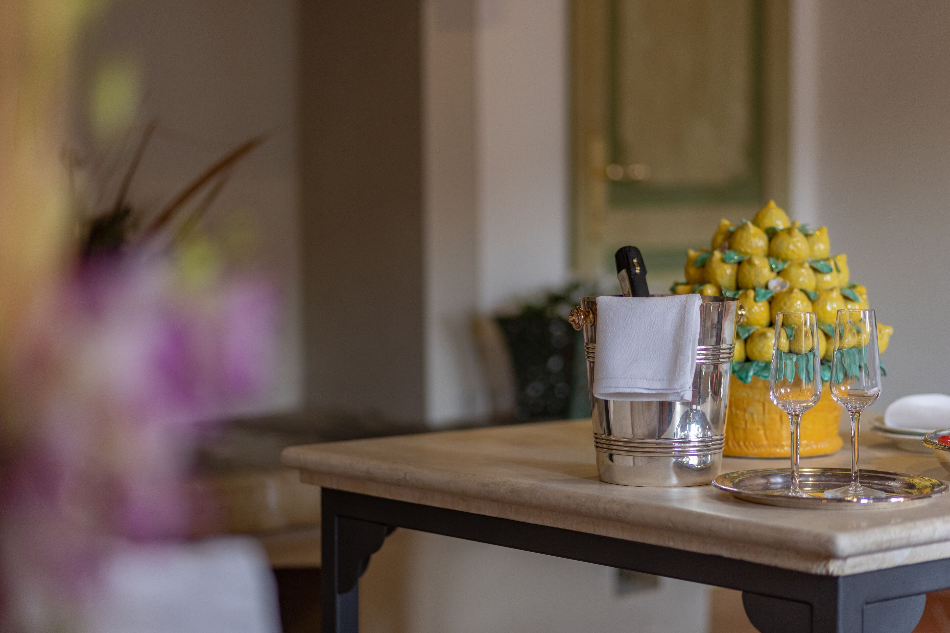 A table with a decorative arrangement of lemons and glasses, a salt shaker, and a napkin holder.