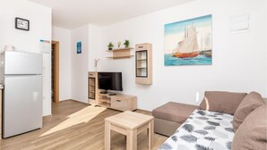 Una sala de estar moderna con un televisor de pantalla plana, muebles de madera, una mesita y un cuadro de un velero.