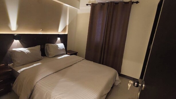 Habitación de hotel con cama, mesitas de noche y una puerta con llaves en el suelo.