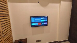 Televisor de pared en una habitación de hotel con una puerta de listones de madera y una pequeña mesa de madera.