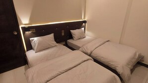 Habitación de hotel con dos camas, cada una con cabecero y almohadas.