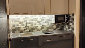 Una cocina con armarios color beige, protector contra salpicaduras de piedra, un microondas y un lavamanos.