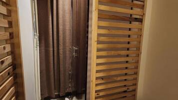 Une porte en bois dotée d’un système coulissant, un rideau et un mur recouvert de panneaux en bois.